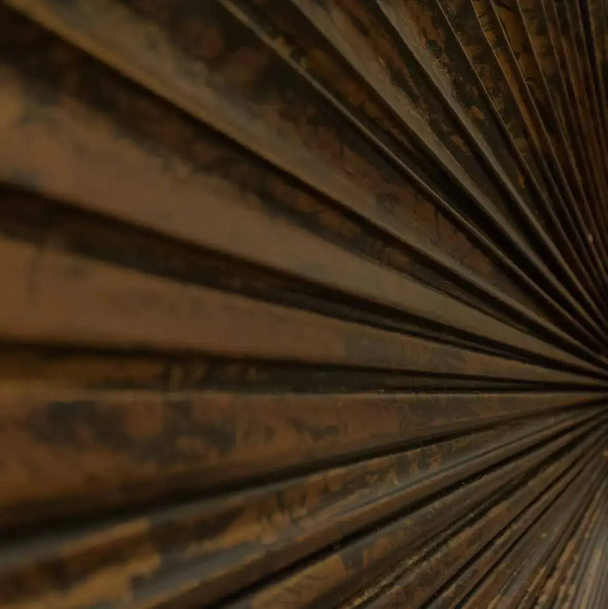 Detail of a pleated bronze surface fanning out from a single point
