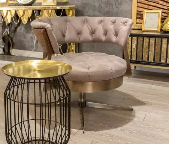 Blush buttoned swivel armchair beside a wire side table with a brass tray top
