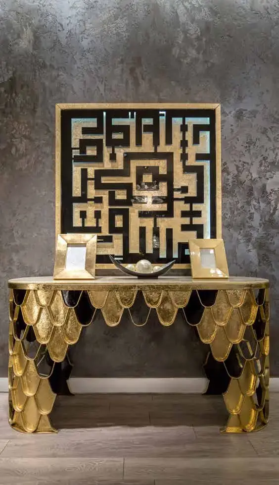 Scalloped gold console table below a square artwork of interlocking Kufic calligraphy