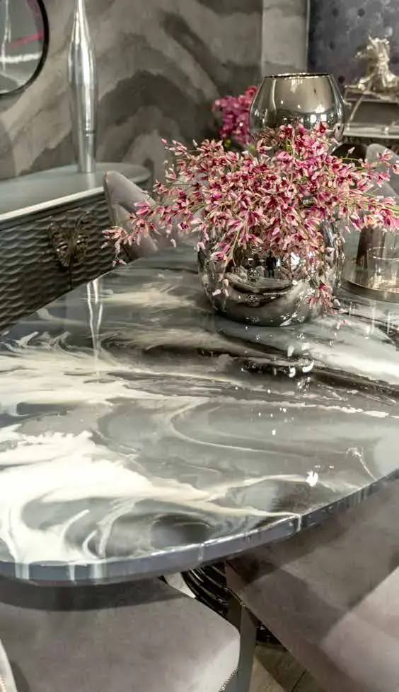 Grey and white marbled round table top holding a silver vase of pink blossom