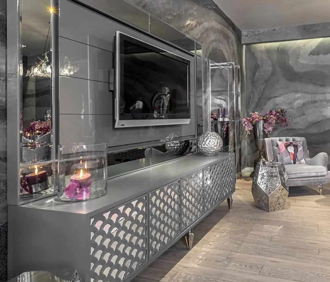 Mirrored media unit with faceted silver doors, lit candles along the top and an agate-patterned wall behind